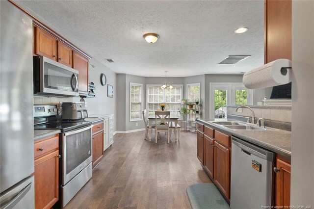 1624 Citation Ct, Parkton, NC 28371 - kitchen with stainless steel appliances, dark wood-type flooring, brown cabinets, a textured ceiling, and a chandelier