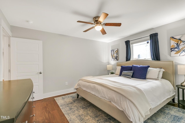 bedroom with dark wood-style floors, a ceiling fan, and baseboards