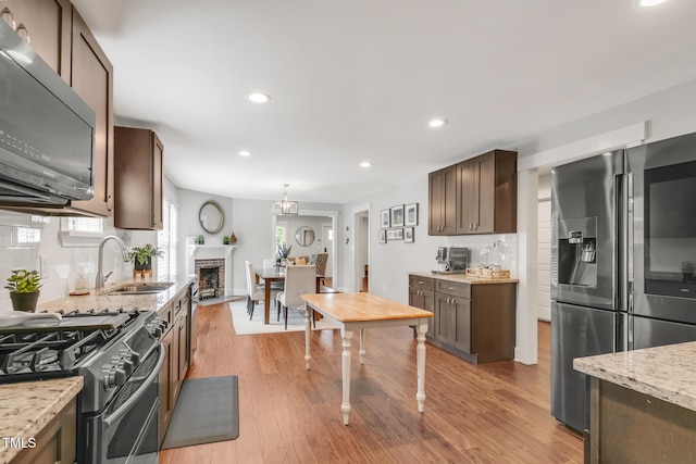 kitchen featuring stainless steel appliances, a sink, decorative backsplash, light wood finished floors, and recessed lighting