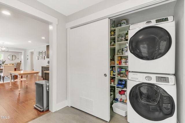 laundry room with estacked washer and dryer, recessed lighting, and tile patterned floors