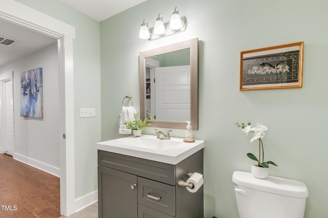 bathroom with toilet, baseboards, wood finished floors, and vanity