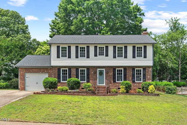 5409 Knollwood Rd, Raleigh, NC 27609 - colonial home with a chimney, brick siding, an attached garage, a front yard, and concrete driveway