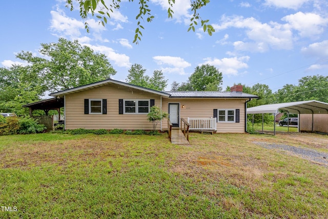 back of property with a yard, a chimney, a carport, driveway, and metal roof