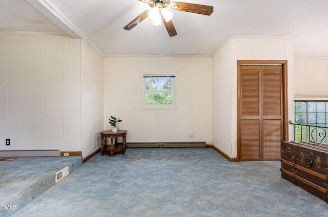 carpeted spare room with ceiling fan, a baseboard radiator, crown molding, and wood walls
