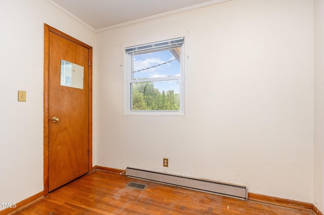foyer featuring baseboard heating, wood finished floors, baseboards, and ornamental molding