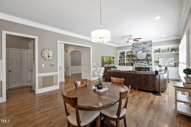 117 Synandra Ln, Holly Springs, NC 27540 - dining area featuring arched walkways, a stone fireplace, built in shelves, ceiling fan, and wood finished floors