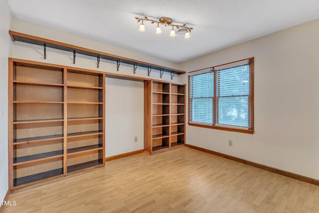 unfurnished bedroom featuring wood finished floors, baseboards, a textured ceiling, and a closet