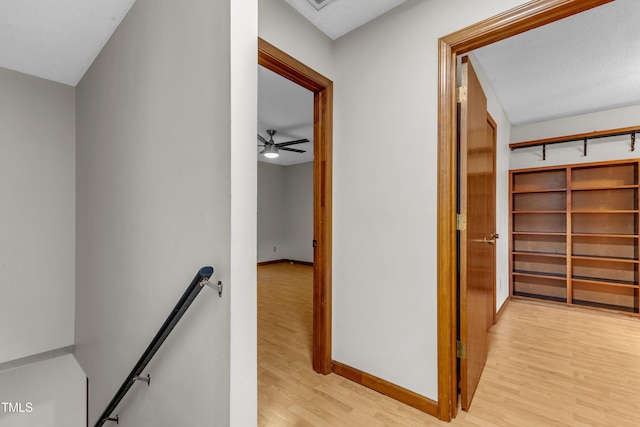 hall featuring an upstairs landing, light wood-style floors, and baseboards