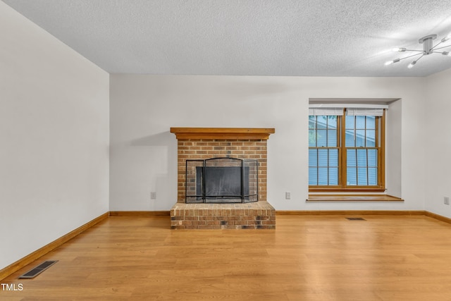 unfurnished living room with wood finished floors, a textured ceiling, baseboards, and a fireplace