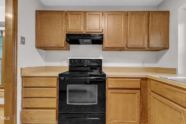 kitchen featuring black electric range, range hood, and light countertops