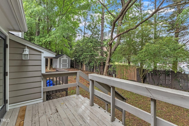 wooden deck with a shed, a fenced backyard, and an outbuilding