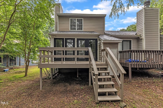 back of house featuring a chimney, stairway, a wooden deck, and a shingled roof