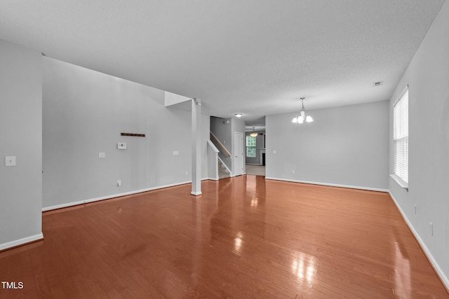 3705 Rivermist Dr, Raleigh, NC 27610 - unfurnished living room featuring wood finished floors, a chandelier, stairway, plenty of natural light, and a textured ceiling