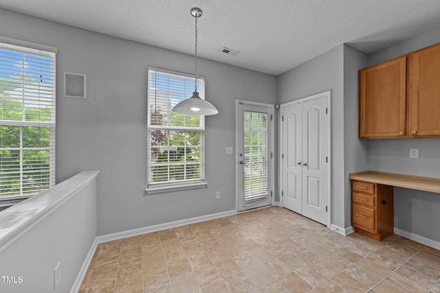 3705 Rivermist Dr, Raleigh, NC 27610 - kitchen featuring a textured ceiling, baseboards, decorative light fixtures, brown cabinetry, and light countertops
