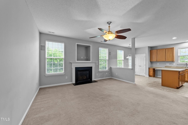 3705 Rivermist Dr, Raleigh, NC 27610 - unfurnished living room featuring baseboards, light colored carpet, a ceiling fan, a fireplace with flush hearth, and a textured ceiling