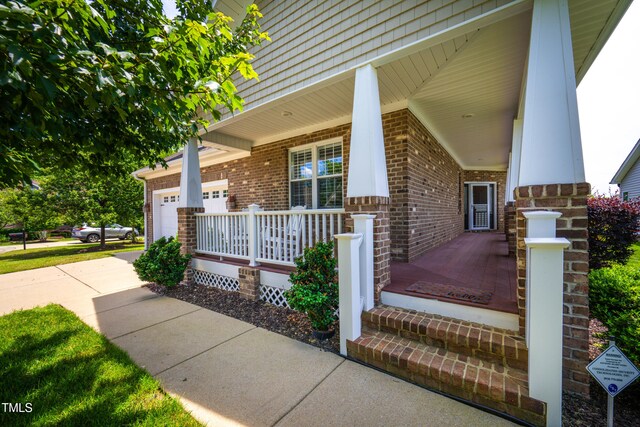 1218 Crystalwater Dr, Fuquay Varina, NC 27526 - doorway to property with a porch, brick siding, concrete driveway, and a garage
