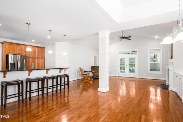 1218 Crystalwater Dr, Fuquay Varina, NC 27526 - kitchen featuring stainless steel refrigerator with ice dispenser, decorative columns, open floor plan, a kitchen bar, and brown cabinetry