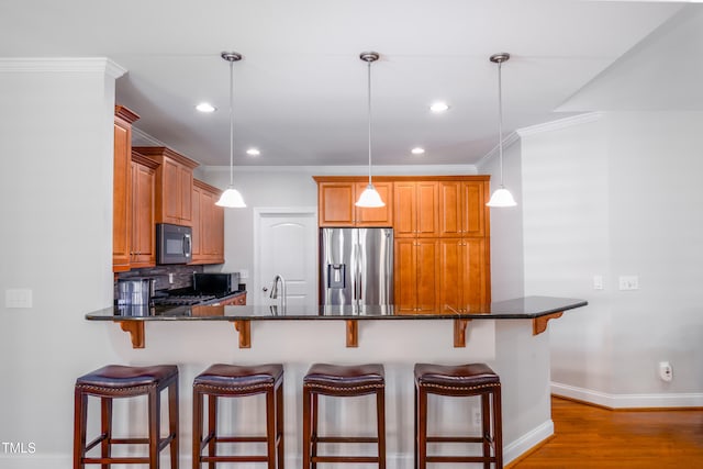 1218 Crystalwater Dr, Fuquay Varina, NC 27526 - kitchen with appliances with stainless steel finishes, a breakfast bar area, light wood-style flooring, brown cabinets, and recessed lighting