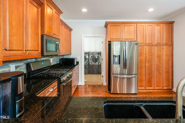 1218 Crystalwater Dr, Fuquay Varina, NC 27526 - kitchen with appliances with stainless steel finishes, separate washer and dryer, ornamental molding, decorative backsplash, and brown cabinetry