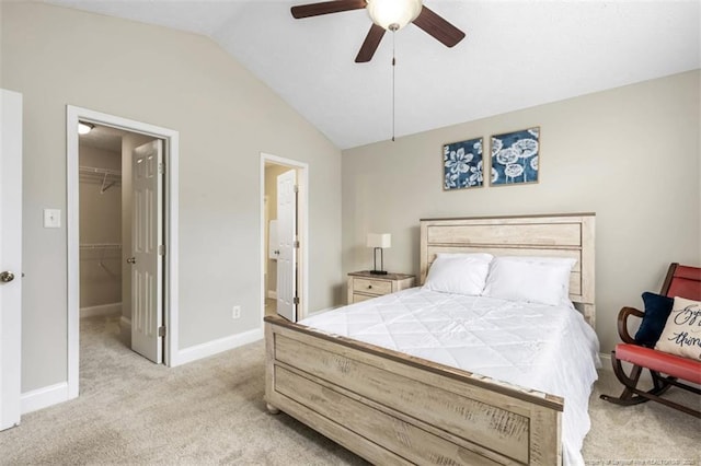 bedroom featuring a spacious closet, lofted ceiling, light colored carpet, a closet, and baseboards