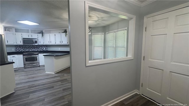 303 Nash Rd, Saint Pauls, NC 28384 - kitchen featuring stainless steel appliances, dark countertops, dark wood-style flooring, white cabinets, and crown molding