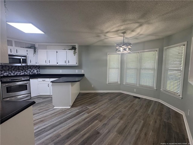 303 Nash Rd, Saint Pauls, NC 28384 - kitchen featuring stainless steel appliances, a peninsula, dark countertops, white cabinets, and a chandelier