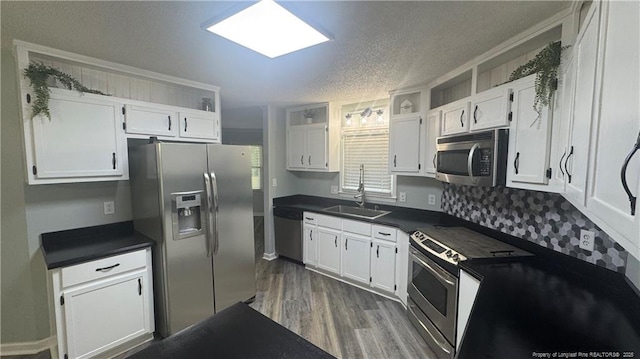 303 Nash Rd, Saint Pauls, NC 28384 - kitchen featuring appliances with stainless steel finishes, a sink, dark countertops, dark wood-style floors, and white cabinetry