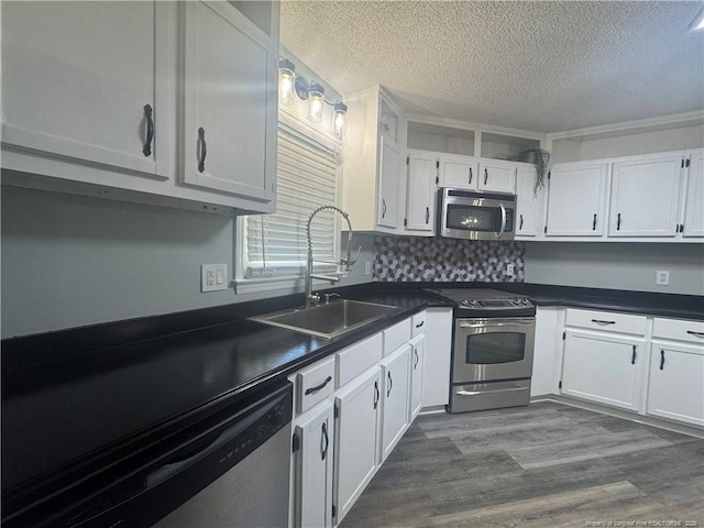 303 Nash Rd, Saint Pauls, NC 28384 - kitchen featuring stainless steel appliances, a sink, a textured ceiling, dark countertops, and white cabinets