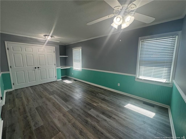 303 Nash Rd, Saint Pauls, NC 28384 - unfurnished bedroom with ornamental molding, a wainscoted wall, multiple windows, a textured ceiling, and dark wood-style flooring