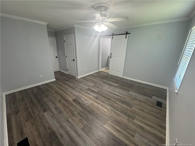303 Nash Rd, Saint Pauls, NC 28384 - unfurnished bedroom with a barn door, dark wood-style floors, baseboards, crown molding, and a textured ceiling
