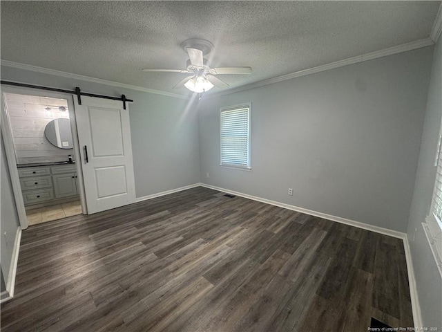 303 Nash Rd, Saint Pauls, NC 28384 - unfurnished bedroom with a barn door, dark wood finished floors, crown molding, baseboards, and a textured ceiling