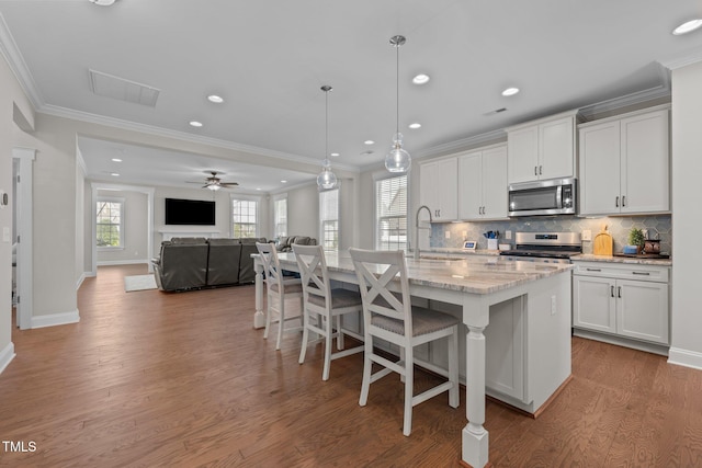 2096 Dowell Ct, Burlington, NC 27215 - kitchen featuring appliances with stainless steel finishes, a sink, ornamental molding, wood finished floors, and decorative backsplash
