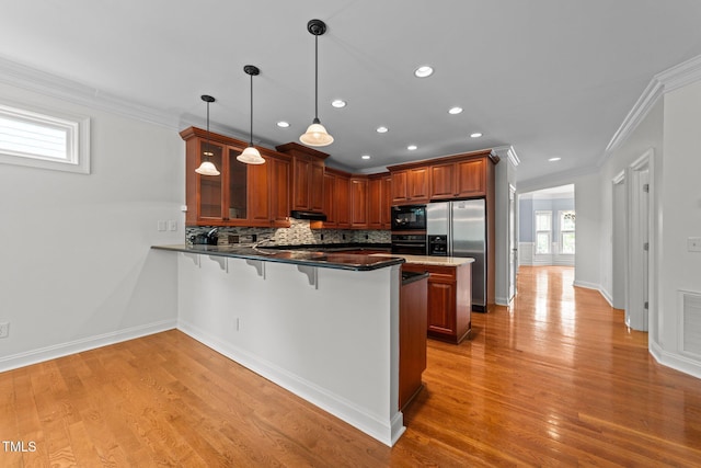 kitchen featuring black appliances, crown molding, a kitchen bar, a peninsula, and plenty of natural light
