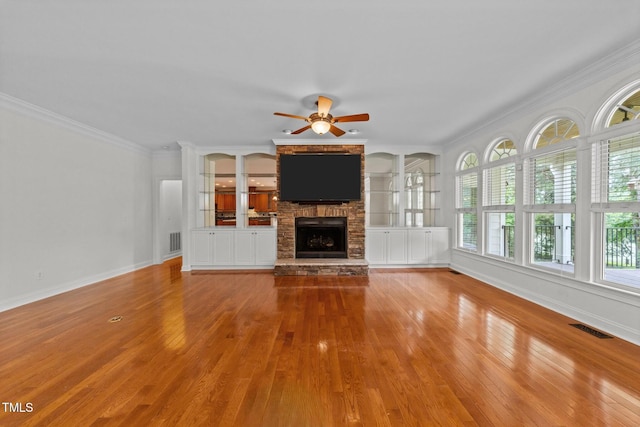 unfurnished living room featuring a ceiling fan, wood finished floors, ornamental molding, a fireplace, and baseboards