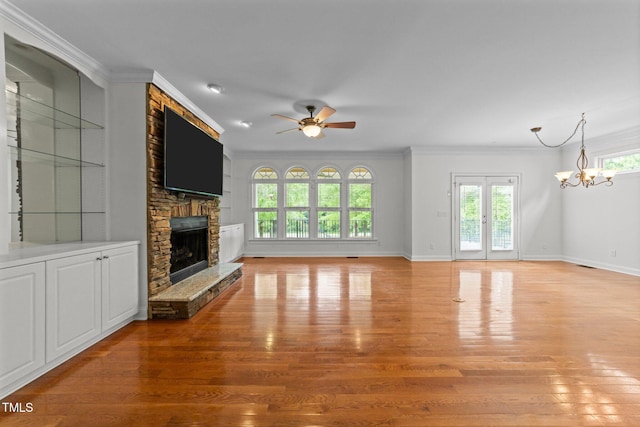 unfurnished living room featuring ceiling fan, light wood-style floors, a fireplace, a chandelier, and baseboards
