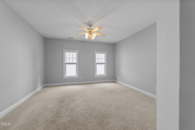 empty room featuring a ceiling fan, baseboards, and light carpet