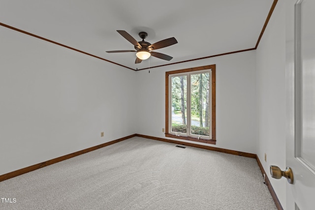carpeted spare room featuring baseboards, ceiling fan, and crown molding