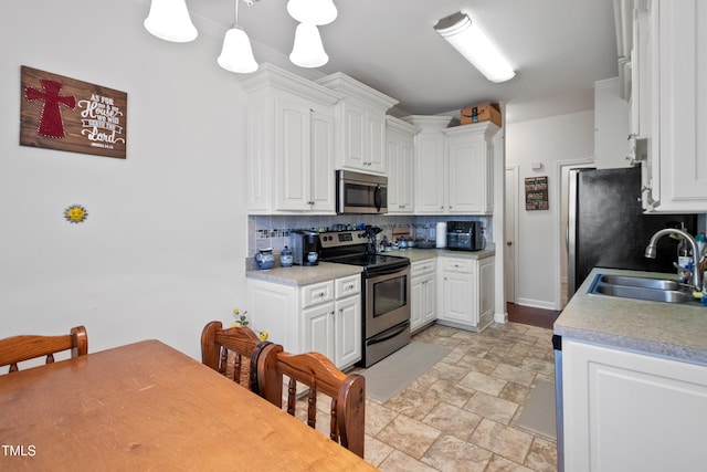 100 Jonathans Pl, Goldsboro, NC 27534 - kitchen with appliances with stainless steel finishes, a sink, stone finish floors, decorative backsplash, and white cabinetry