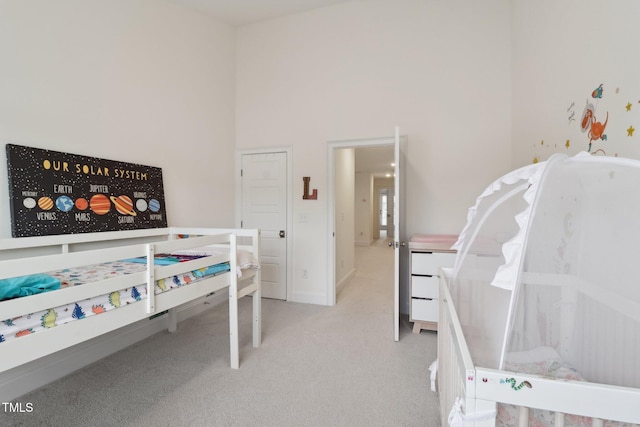 carpeted bedroom with baseboards and a high ceiling
