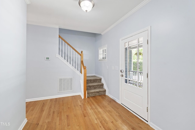 foyer with stairway, crown molding, light wood-style floors, and baseboards
