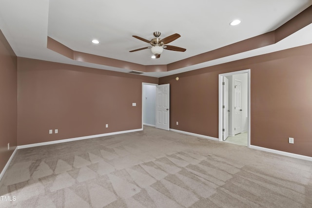 empty room featuring ceiling fan, baseboards, light colored carpet, recessed lighting, and a tray ceiling