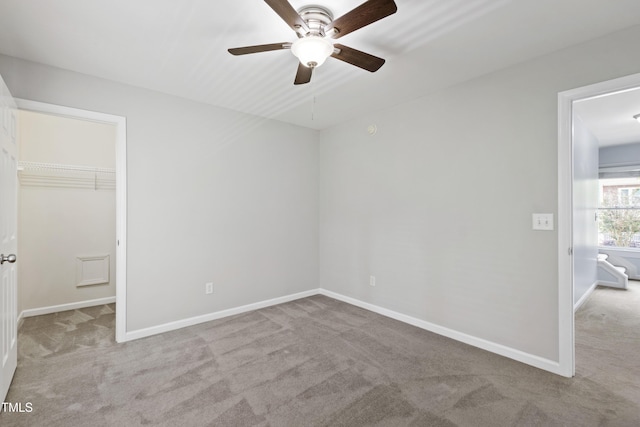 unfurnished bedroom with carpet floors, a walk in closet, and baseboards
