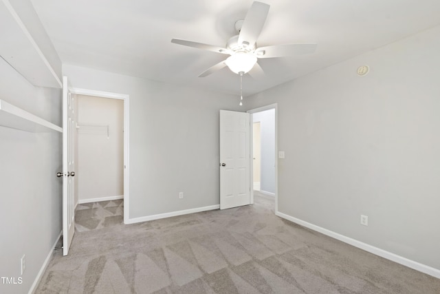 unfurnished bedroom with a closet, baseboards, carpet, and a spacious closet
