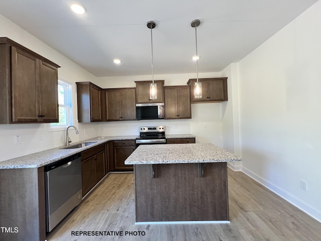 kitchen with stainless steel appliances, a sink, dark brown cabinets, light wood finished floors, and recessed lighting