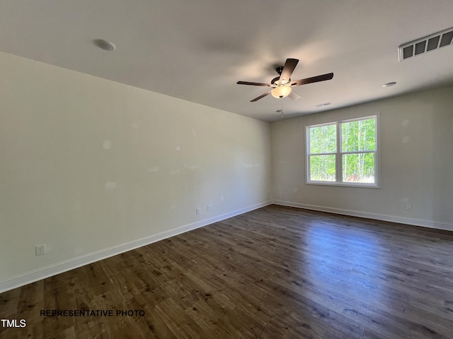 spare room with a ceiling fan, dark wood-style floors, and baseboards