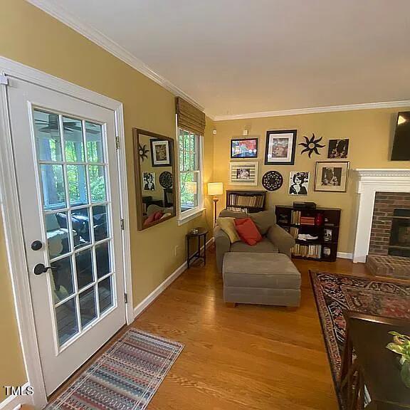 sitting room featuring wood finished floors, crown molding, baseboards, and a fireplace