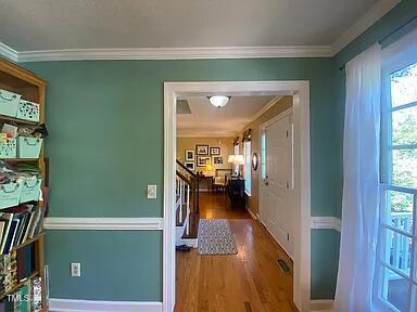 hall featuring wood finished floors, crown molding, stairway, and baseboards