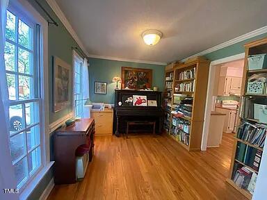 living area featuring crown molding, healthy amount of natural light, and wood finished floors