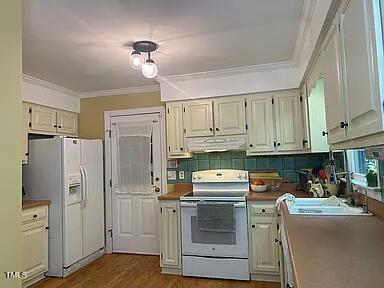 kitchen with white appliances, under cabinet range hood, crown molding, wood finished floors, and tasteful backsplash
