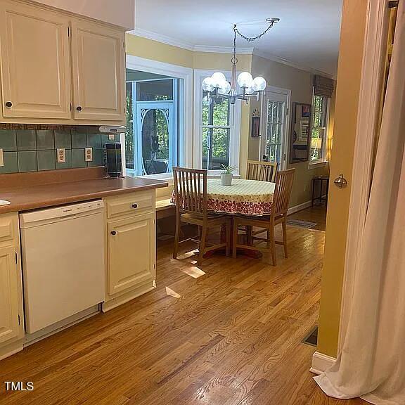 dining space featuring ornamental molding, a chandelier, light wood-type flooring, and plenty of natural light